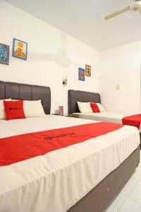 1 Schlafzimmer mit 2 Betten mit roter und weißer Bettwäsche in der Unterkunft RedDoorz near Pojok Beteng Prawirotaman in Yogyakarta