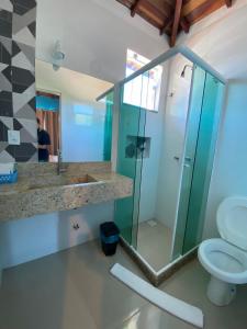 uma casa de banho com uma cabina de duche em vidro e um WC. em Foca Guest House em Búzios