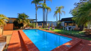 a swimming pool in the backyard of a house with palm trees at Hilltop Motel in Broken Hill