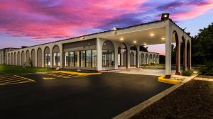 un edificio con un estacionamiento con un cielo nublado en HomeTowne Studios by Red Roof Chicago - N Aurora-Naperville en North Aurora