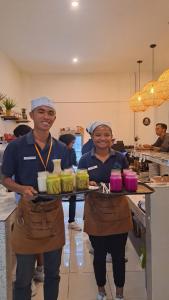 two women in a kitchen holding a tray of food at Anjo Maumere Hotel & Restaurant in Nangalima