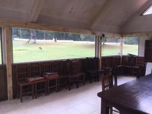 un restaurante con mesas y sillas de madera y un perro en un campo en Rancho Ecológico El Mirador, en Acajete