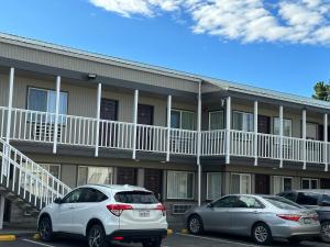 dos autos estacionados en un estacionamiento frente a un edificio en Royal Victorian Motel en Port Angeles