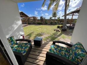 a porch with two chairs and a view of a yard at Te Mao in Avatoru