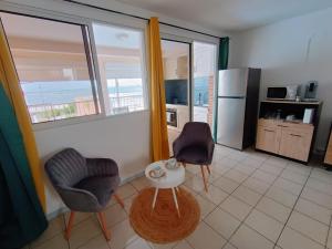 una cocina con 2 sillas y una mesa en una habitación en Cibuqueira numéro 5, Appartement en centre ville,vue sur mer, plage à pied, en Le Moule