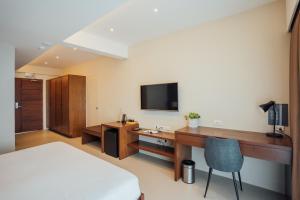 Schlafzimmer mit einem Bett und einem Schreibtisch mit einem TV in der Unterkunft Solitude Acacia Resort in Mabini