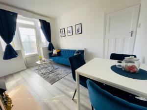 uma sala de estar com uma mesa branca e cadeiras azuis em Central Luton 4 Bedroom home✪parking✪By Hostaguest em Luton