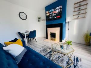 a living room with a blue couch and a fireplace at Central Luton 4 Bedroom home✪parking✪By Hostaguest in Luton
