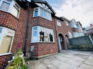 a red brick house with a lot of windows at Central Luton 4 Bedroom home✪parking✪By Hostaguest in Luton