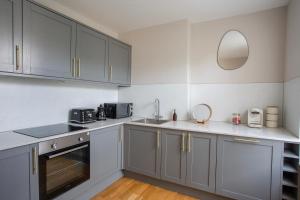 Eden Grove - Islington - Studio Apartment في لندن: مطبخ بدولاب رمادي ومغسلة