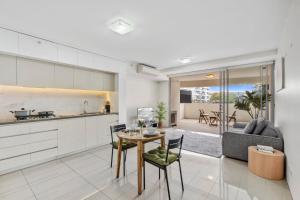 a kitchen and living room with a table and chairs at Modern Riverside Oasis - Gym Pool WiFi & Parking in Brisbane