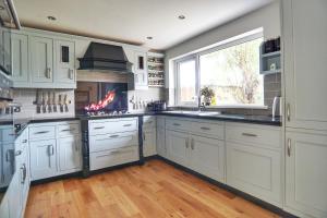 a kitchen with white cabinets and a large window at Warm and Spacious 4BD Family Retreat with Garden in Plymouth