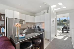 a kitchen with white cabinets and a purple couch at Marina View Apartment - Taupo in Taupo