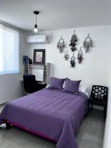 - une chambre avec un lit violet et une chaise dans l'établissement CasaMuyuyo - Hermosa Casa de Playa a 1h20 de Guayaquil, à Playas
