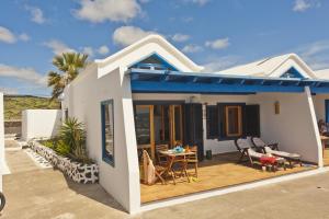 a white house with a blue roof and a patio at Casita Lanzaocean view in Punta de Mujeres