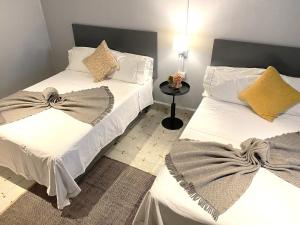 2 łóżka w pokoju z białą pościelą i poduszkami w obiekcie Hotel El Pedregal w mieście Matehuala