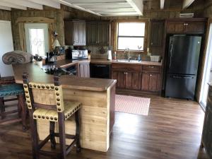 a kitchen with wooden cabinets and a black refrigerator at Rockin' B Ranch Bluff House in Pipe Creek