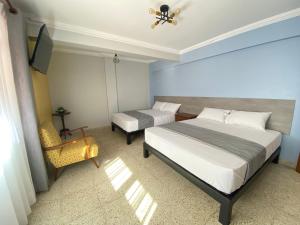 a bedroom with two beds and a tv and a chair at Izza Hotel in Cochabamba