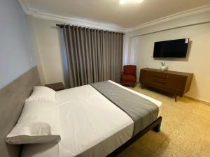 een slaapkamer met een bed en een flatscreen-tv bij Izza Hotel in Cochabamba