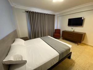 a bedroom with a bed and a flat screen tv at Izza Hotel in Cochabamba