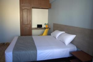 een slaapkamer met een bed met witte lakens en kussens bij Izza Hotel in Cochabamba