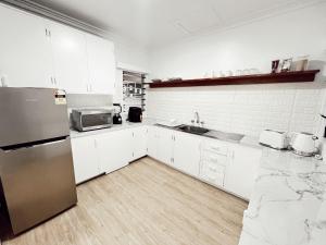 a kitchen with white cabinets and a stainless steel refrigerator at Gladstone Gem 6 - Suva CBD 2bdrm Apts in Suva