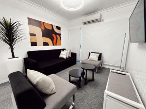 a living room with a black couch and a chair at Gladstone Gem 6 - Suva CBD 2bdrm Apts in Suva