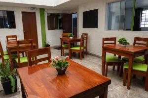 um restaurante com mesas de madeira, cadeiras e plantas em Green House em Lima