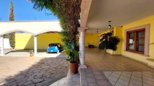 un bâtiment jaune avec une voiture garée dans une cour dans l'établissement Hotel Morada de los Angeles, à Calera Víctor Rosales