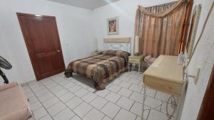 1 dormitorio con cama, mesa y puerta en Hotel Morada de los Angeles, en Calera Víctor Rosales