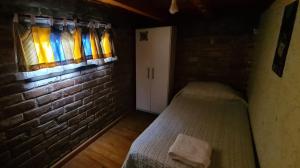 a small room with a bed and a brick wall at Departamento completo in Ciudad Lujan de Cuyo