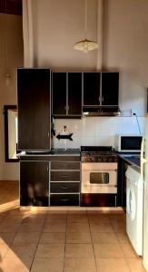 a kitchen with black cabinets and a stove top oven at Departamento completo in Ciudad Lujan de Cuyo