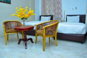 a hotel room with two beds and a table and chairs at Mawuli Hotel in Obuassi