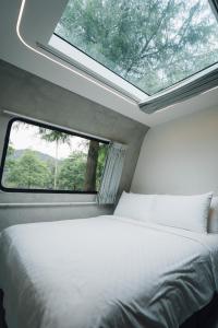 1 dormitorio con cama y ventana en 天ㄟ露營車 en Dongshan