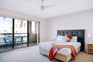 a bedroom with a bed and a balcony with a table at Waterfront Townhouse - One in Port Lincoln