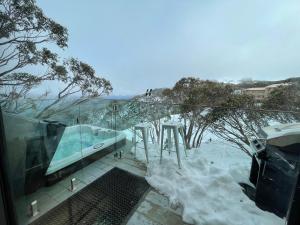 a room with a balcony with snow on the ground at Frostwood in Mount Buller