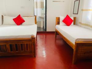 due letti in una stanza con cuscini rossi sopra di Athena Guest House a Trincomalee