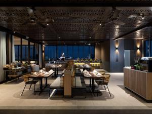 a restaurant with tables and chairs and a bar at Hotel Santika PasirKaliki in Bandung
