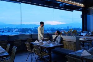 a man and a woman standing at a table in a restaurant at Hotel Santika PasirKaliki in Bandung