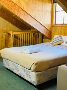 a bed in a room with a wooden wall at Carinya Village Jindabyne in Jindabyne