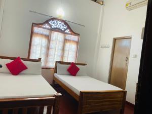 due letti in una stanza con finestra di Athena Guest House a Trincomalee
