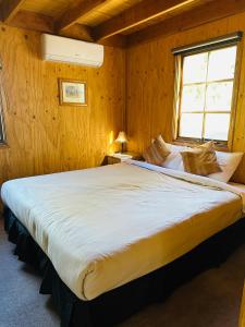 金逹拜恩的住宿－Carinya Village Jindabyne，木制客房内的一间卧室配有一张大床