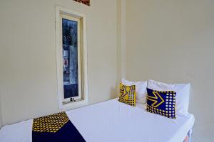 een slaapkamer met een bed met kussens en een raam bij SPOT ON 92799 Tanjung Indah Homestay Syariah in Banyuwangi