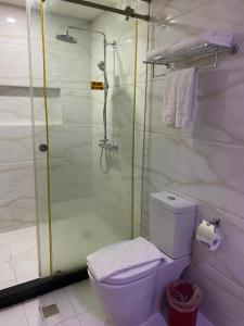 uma casa de banho com um chuveiro, um WC e um rolo de papel higiénico. em Sun Star Grand Hotel em Manila