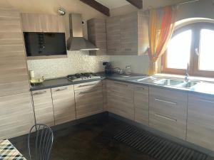 cocina con armarios de madera, fregadero y ventana en La scalinata del Borgo en Montecorvino Rovella