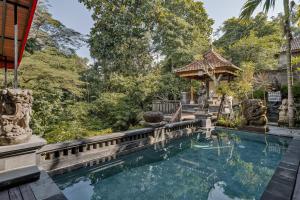 a swimming pool in a backyard with a gazebo at Tigata Ubud Cottage in Ubud