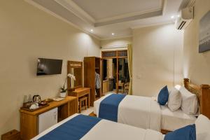 una camera d'albergo con due letti e una televisione di Tigata Ubud Cottage ad Ubud