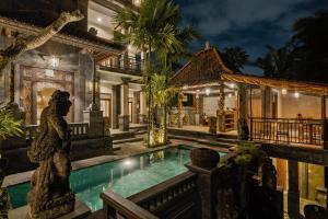 a villa with a statue next to a swimming pool at Tigata Ubud Cottage in Ubud