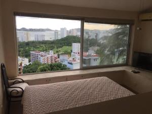 um quarto com uma cama e uma grande janela em Hermosa Villa Puesta al SOL em Acapulco