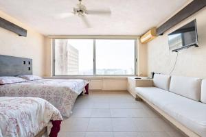 アカプルコにあるHermosa Villa Puesta al SOLのベッドルーム1室(ベッド2台、ソファ、大きな窓付)